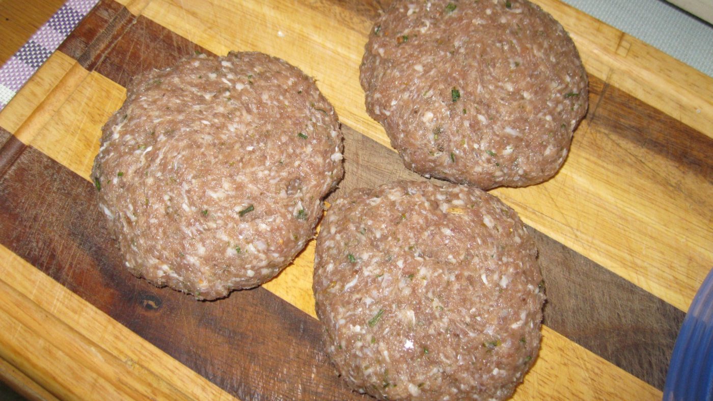 Wurstbrät zur Bulette geformt auf dem Brett wird zur Salami