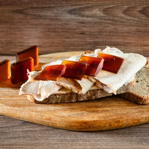 Aufgeschnittener Schweinebraten auf Brot, dazu Gelee-Scheiben als Bratensoße