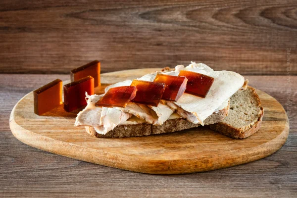 Aufgeschnittener Schweinebraten auf Brot, dazu Gelee-Scheiben als Bratensoße